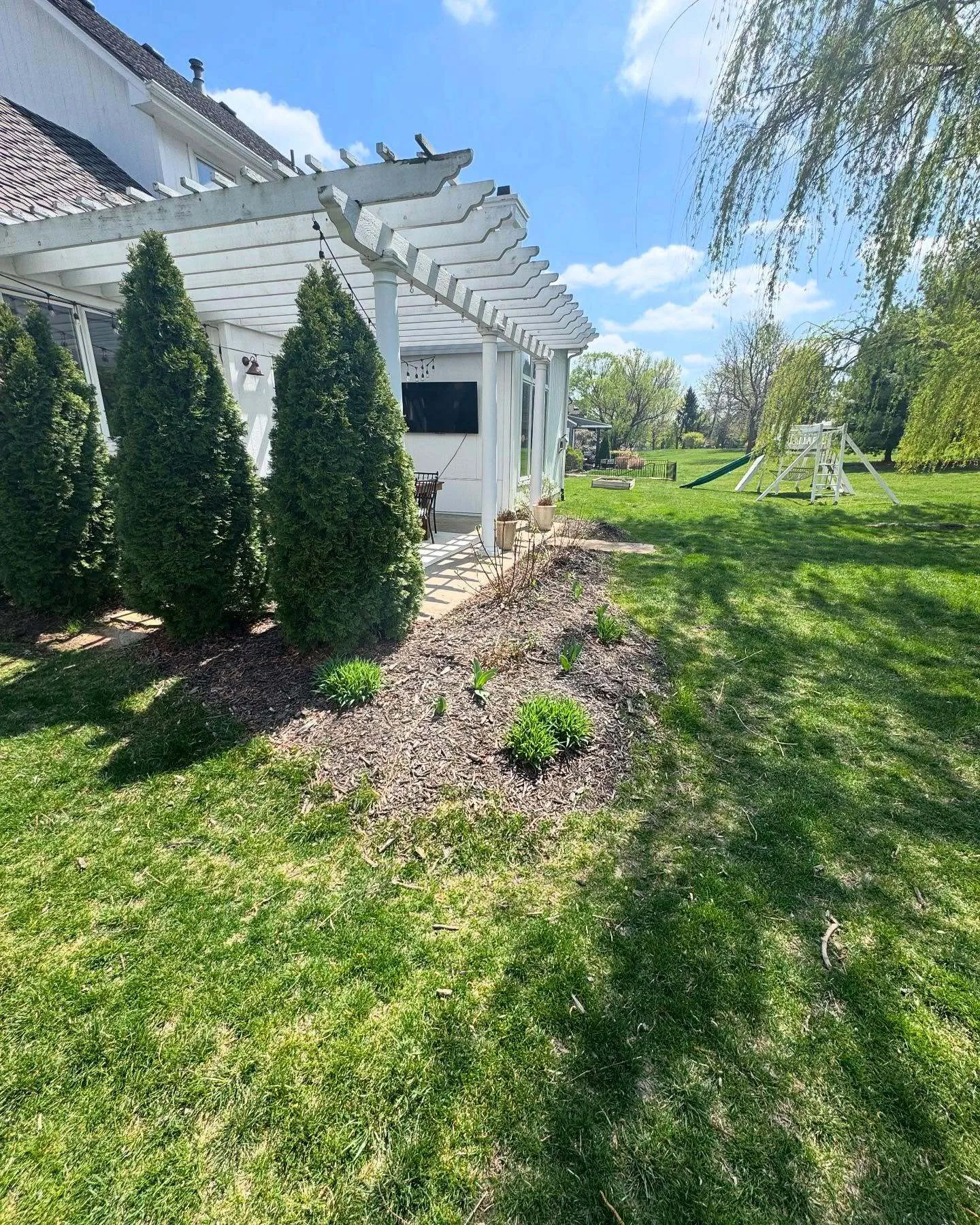 Landscaping around pergola with mulch and plantings