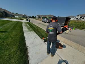 Urban Diamond team member edging a lawn in branded shirt